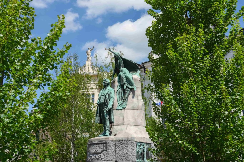 Estátua em homenagem ao poeta mais famoso da Eslovênia, Prešeren, cercada de árvores, bem no meio da Praça Prešeren.