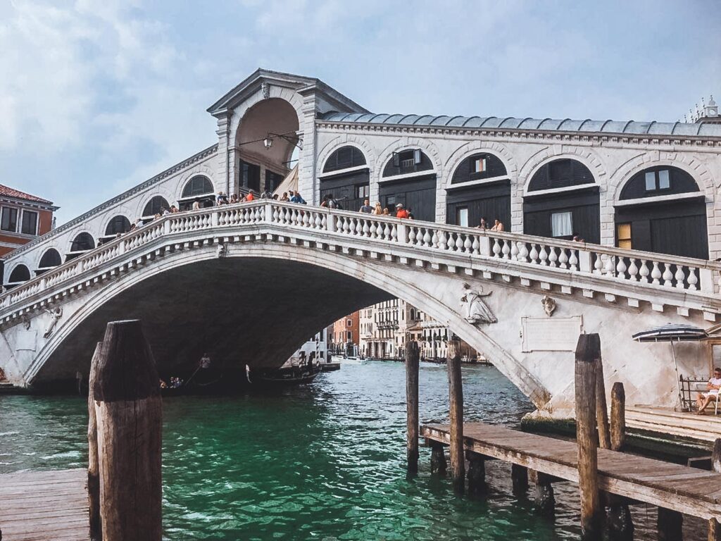 Ponte Rialto vista de baixo, com o Grand Canal de Veneza e movimento de turistas