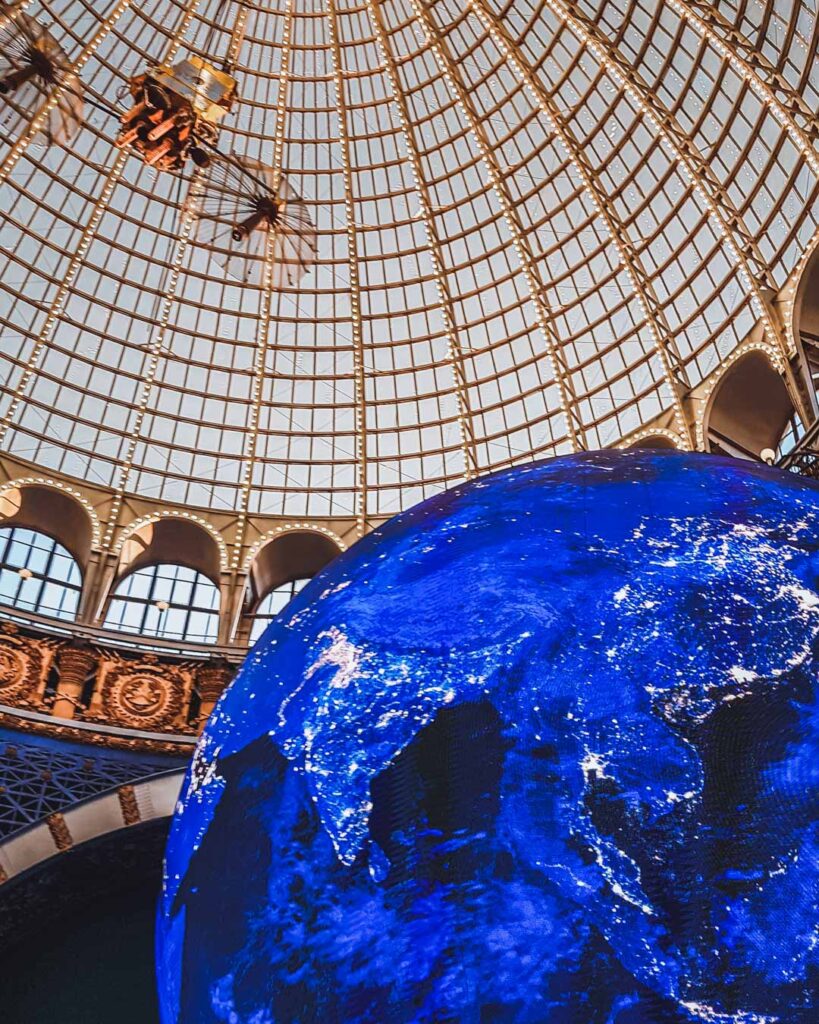 Parte do monumento iluminado do Planeta Terra no interior do Museu do Cosmos, com a cúpula dourada e de vidro em cima.