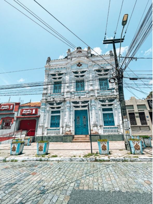 Antigo prédio maçônico em uma rua de pedra no centro histórico de João Pessoa, com fachada azul listrada e com colunas.