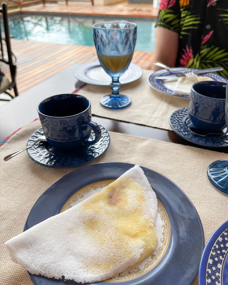 Tapioca do café da manhã na Pousada Morena Flor. Xícaras, pratos e copos azuis.